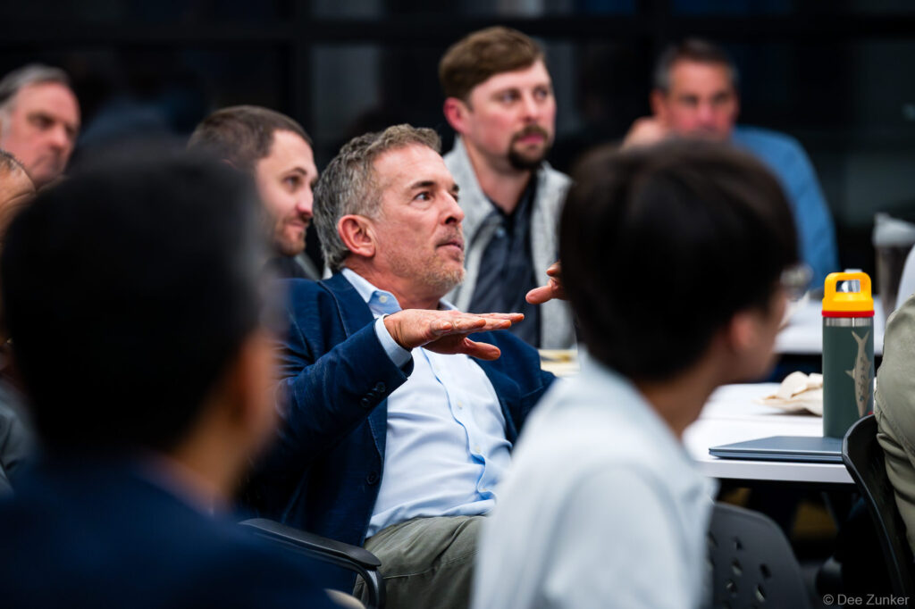 Corporate event attendee in navy blazer gestures during a business meeting, photographed by Houston commercial event photographer.