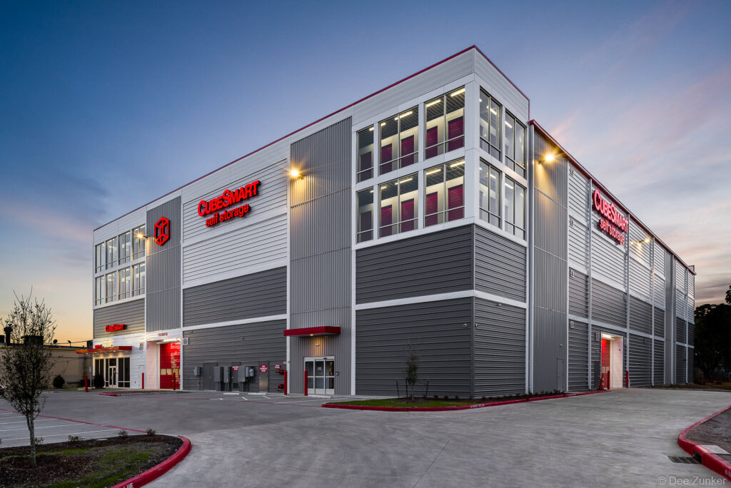Exterior of a multi-story self-storage facility photographed at twilight, showcasing modern metal panel architecture with illuminated signage in Houston, Texas