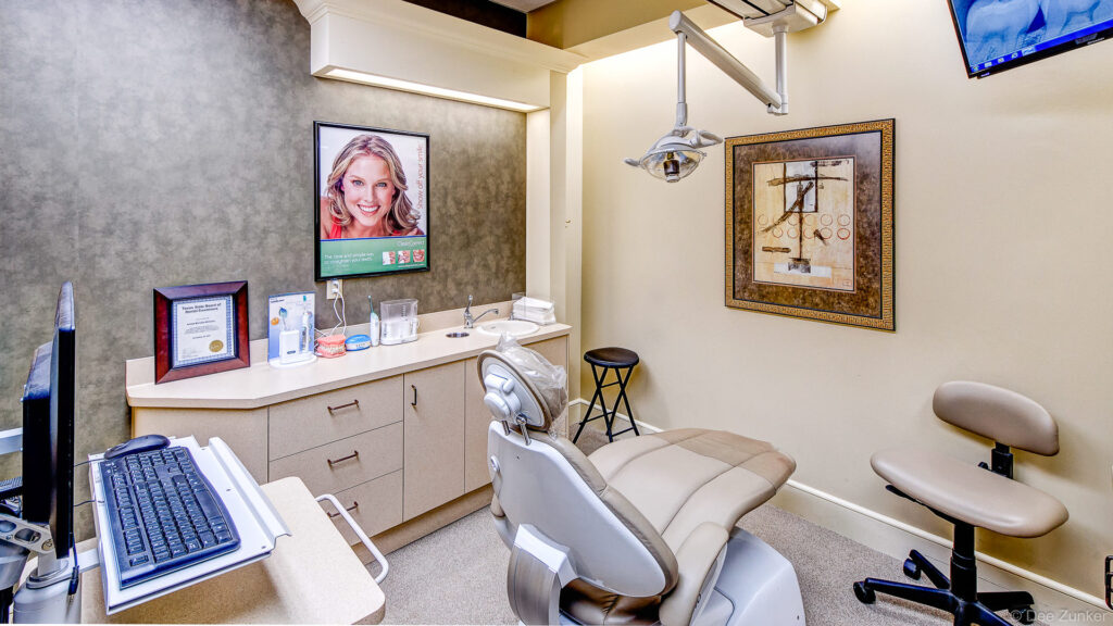Modern dental office treatment room with patient chair, overhead exam light, computer workstation, and cabinetry in The Woodlands TX