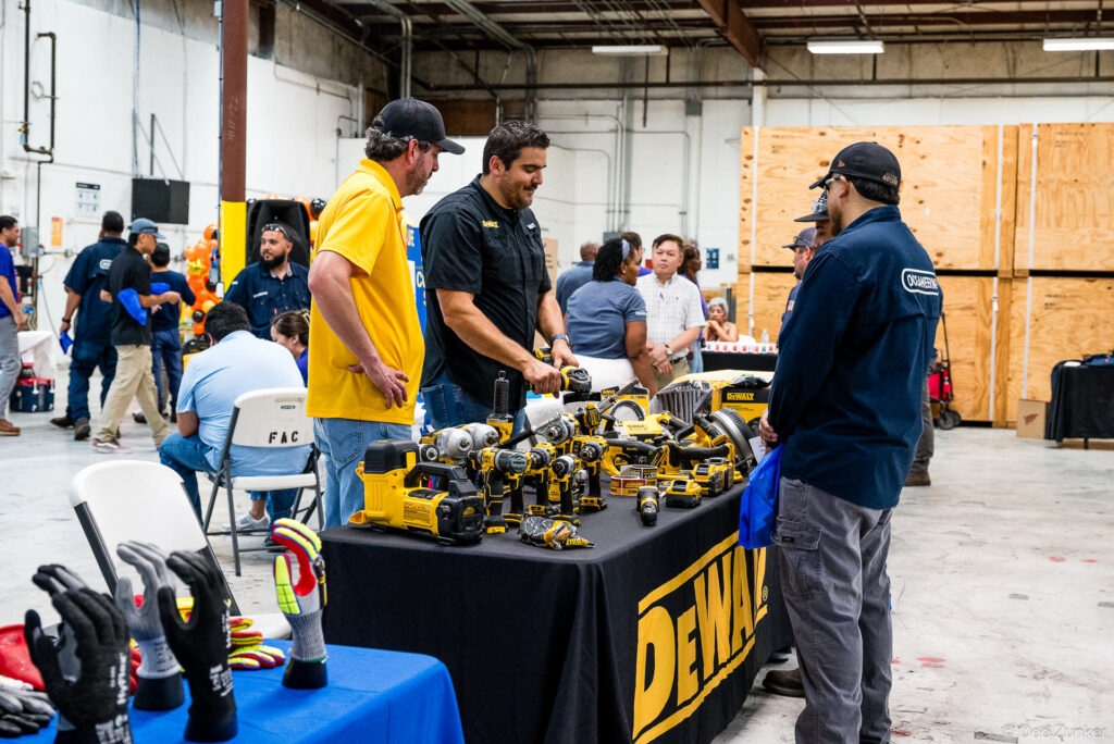 Sales rep demonstrates DeWalt power tools to attendees at a Houston corporate safety day trade show exhibition table.