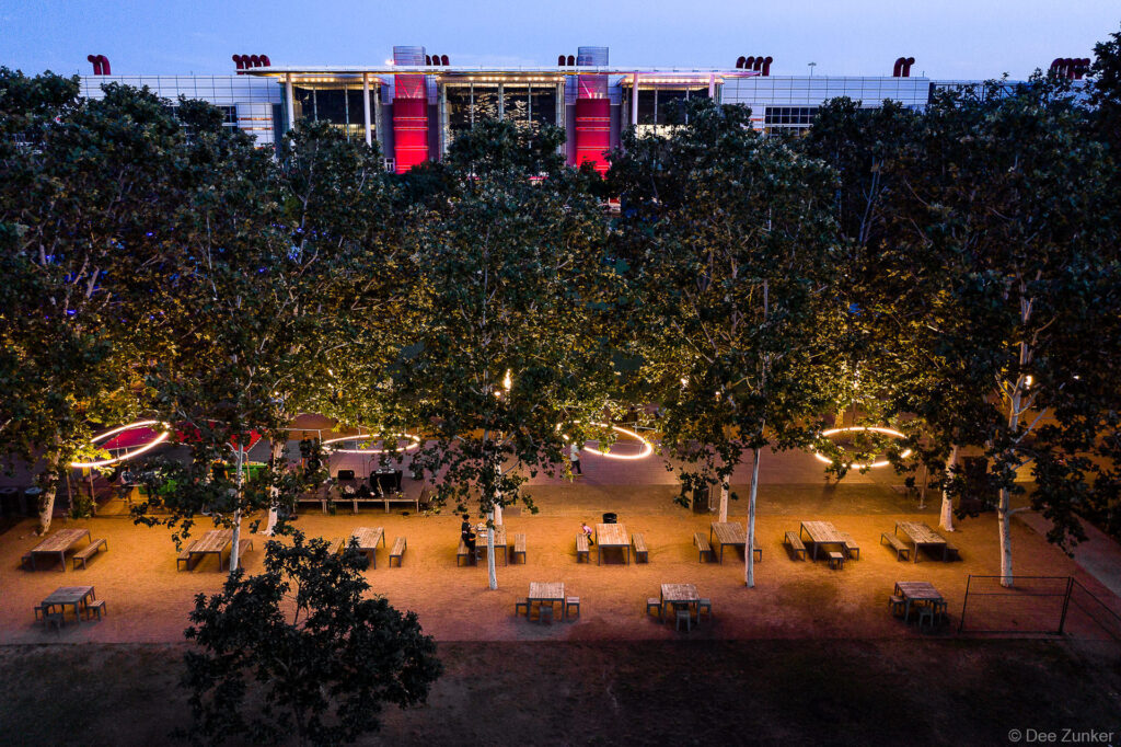 Aerial dusk view of Discovery Green Houston with glowing circular light installations among trees and illuminated outdoor seating area.