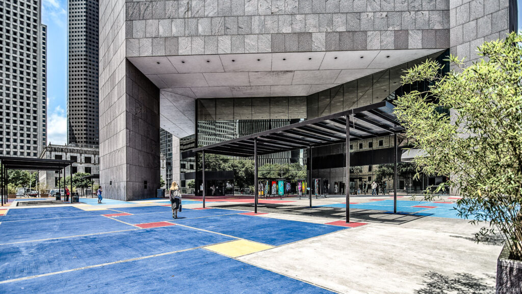 Colorful geometric plaza courtyard at a modernist downtown Houston Library , featuring bold primary-colored pavement and a dramatic cantilevered concrete facade.