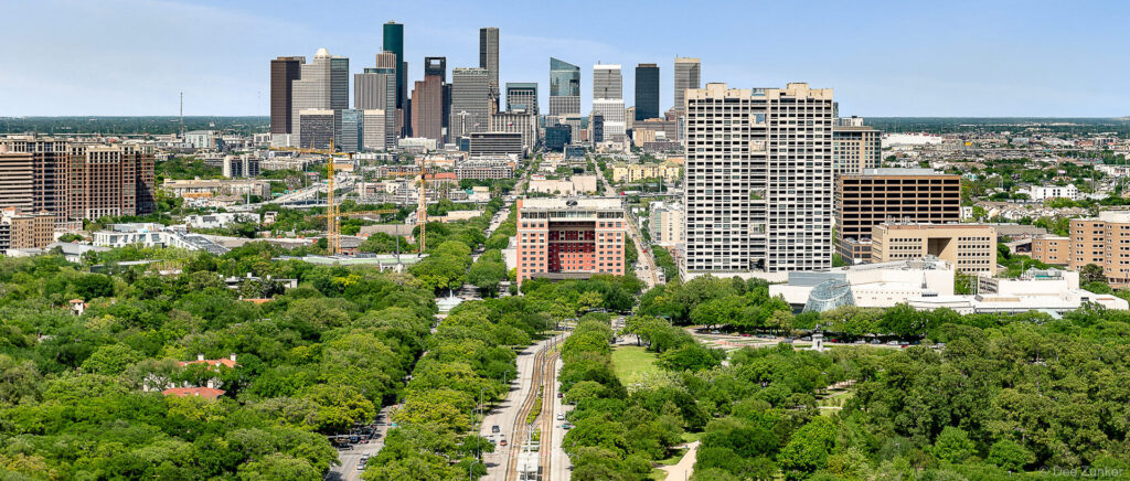 Sunny aerial view looking north over the Texas Medical Center district with the Downtown Houston skyline in the background.
