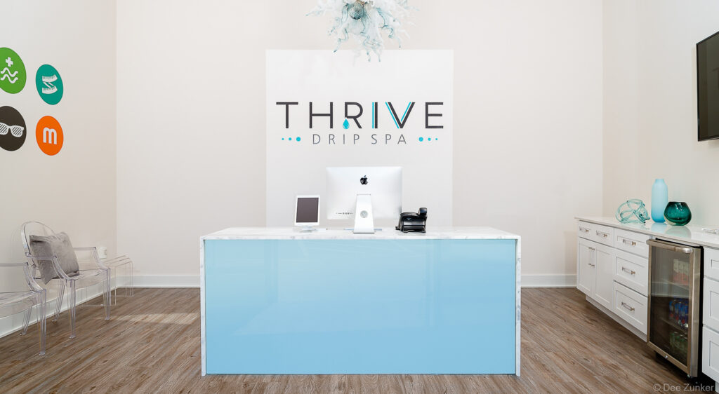 Modern drip spa reception desk with light blue front panel, marble countertop, and Apple iMac in The Woodlands, Texas