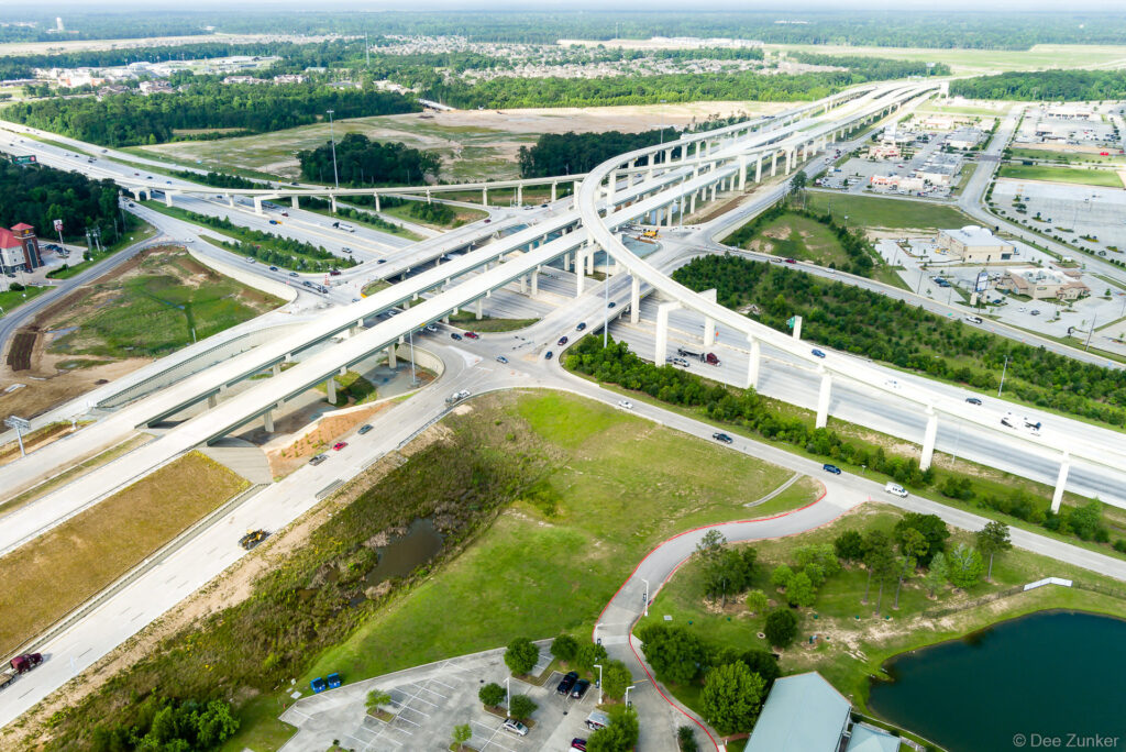 Aerial drone view of Highway 99 and I-10 interchange in Houston TX showing multilevel elevated freeway ramps and surrounding suburban development