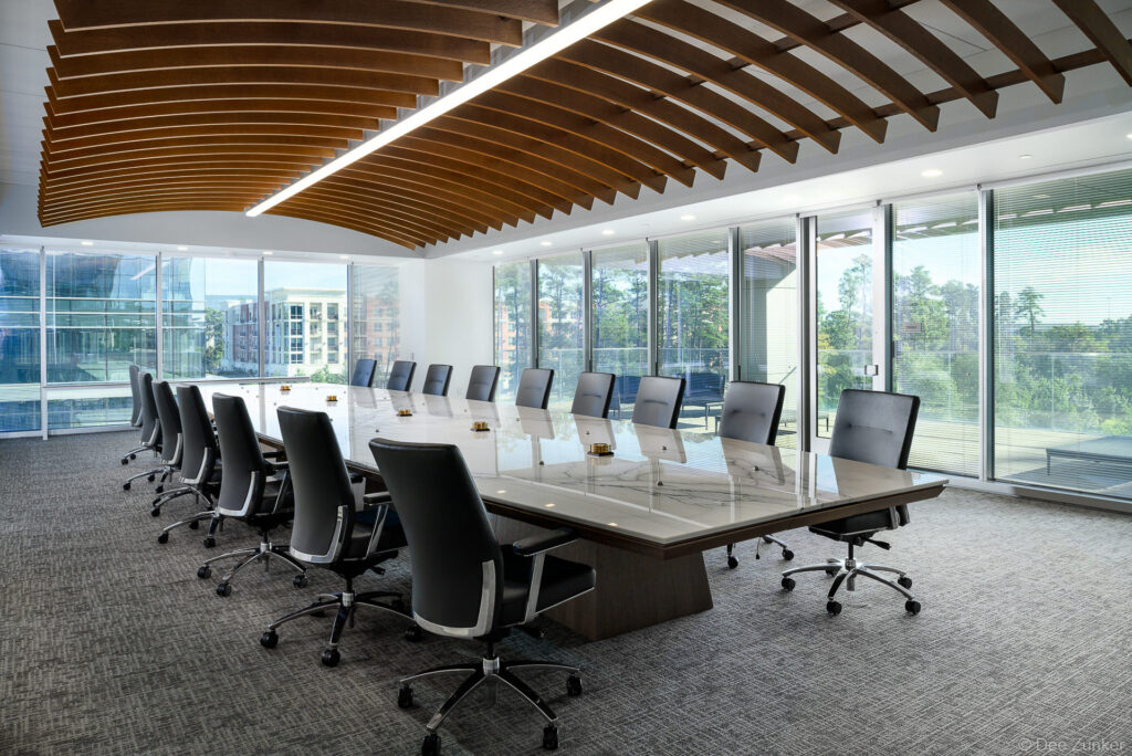 Executive conference room with dramatic ship keel wood ceiling, marble boardroom table, black leather chairs, and floor-to-ceiling windows in Spring, TX