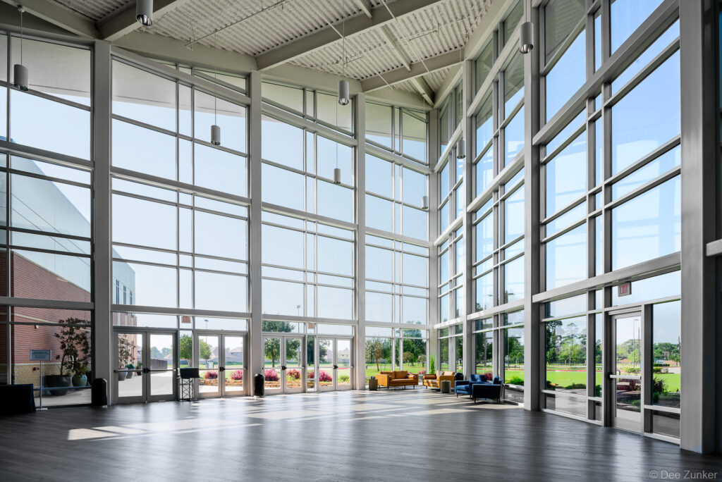Soaring glass curtain wall atrium of a Houston church interior flooded with natural light and modern seating