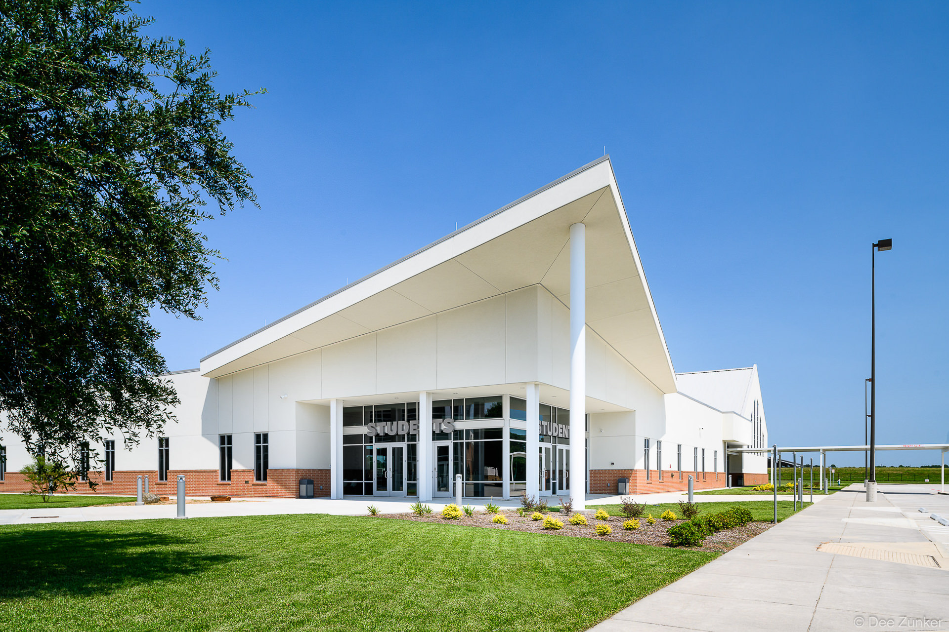 Exterior view of a modern church student center in Spring TX featuring a dramatic angled white roof and glass entry facade