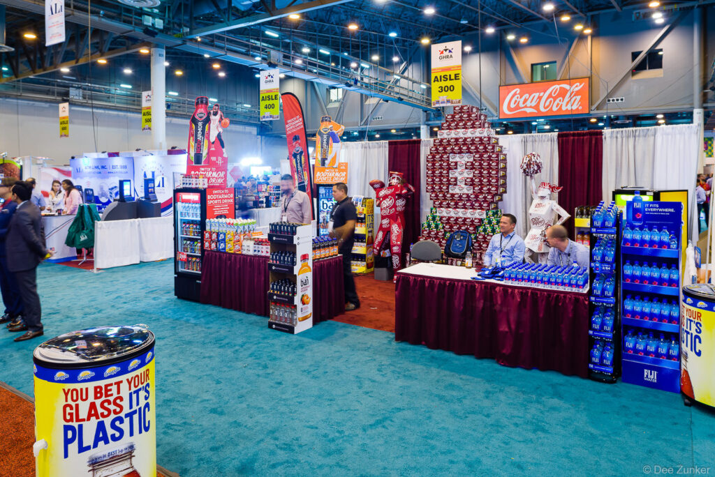 Beverage brand exhibition booths with product displays at a Houston trade show convention center, photographed by commercial event photographer.