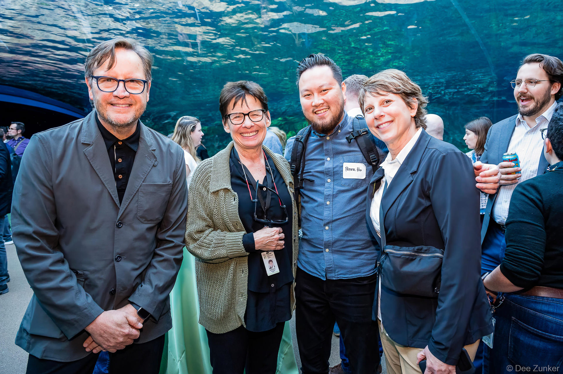 Four professionals including Peter Ho smile together at Gulf Coast Green networking event inside a Houston aquarium venue.
