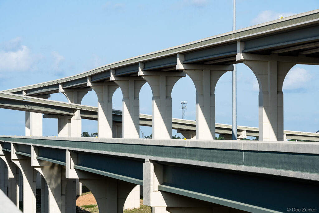 Multi-level concrete highway overpass with arched support columns along Highway 99 Grand Parkway in Houston, Texas.