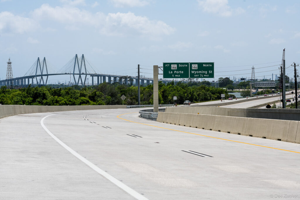 Newly constructed highway interchange on Highway 99 near La Porte with Fred Hartman Bridge cable-stayed span visible in background, Houston Texas.