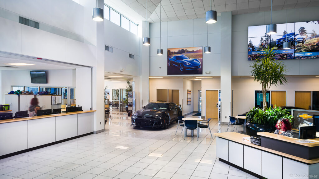 Bright Houston car dealership showroom interior featuring a black sports car on display, seating area, and high ceilings