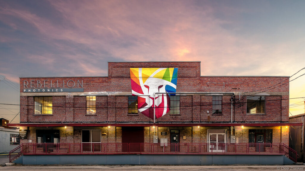 Exterior of a two-story brick commercial building at dusk featuring a colorful mural, Houston architectural photography