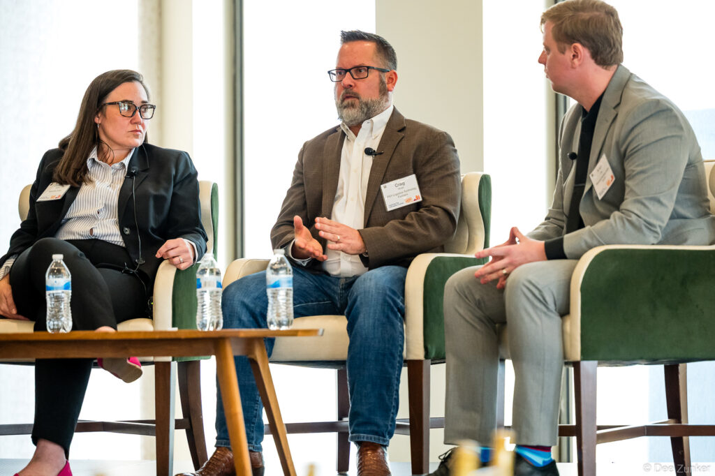 Three panelists seated in green armchairs engage in discussion at a Houston corporate conference, captured by commercial event photographer.