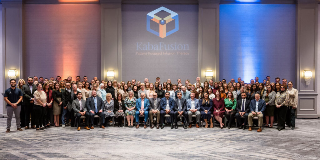 Large corporate group portrait of approximately 150 conference attendees posed in a hotel ballroom in Houston, Texas