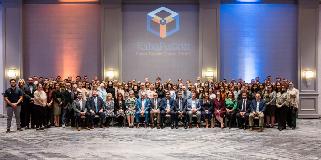 Large corporate conference group photo of approximately 150 professionals posed in rows in a ballroom, Houston Texas