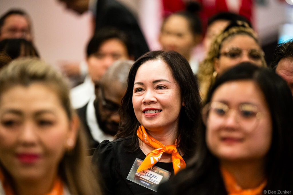 Smiling woman conference attendee wearing orange lanyard and name badge at Houston corporate event