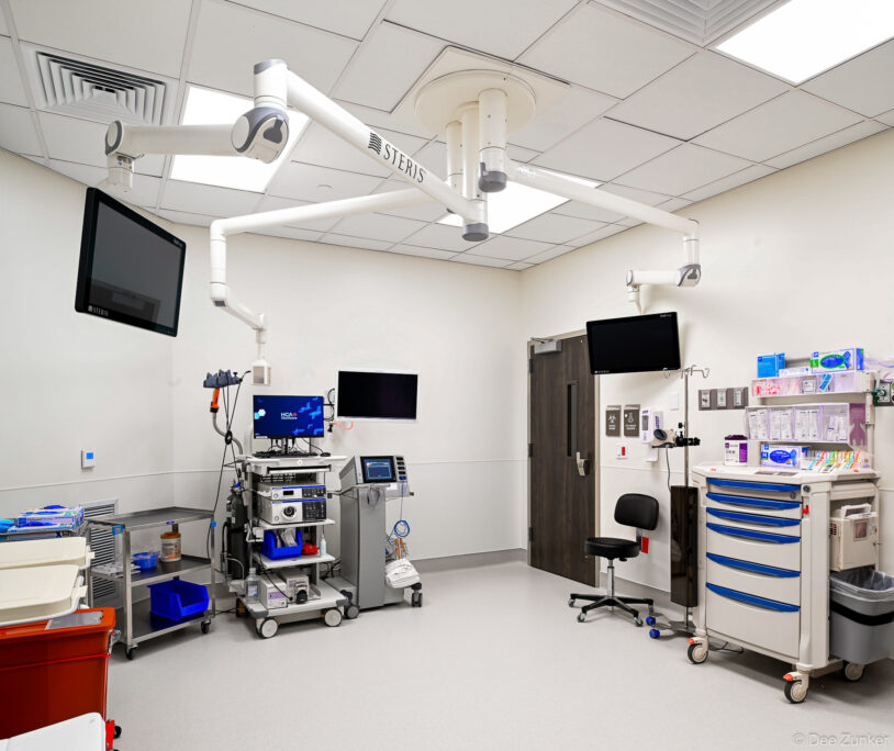 Fully equipped surgical suite with STERIS overhead lights, multiple monitors, medical supply carts, and endoscopy equipment in a Houston hospital.