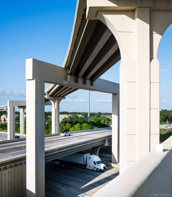 Layered concrete highway interchange showing elevated ramps, support columns, and moving truck at Hwy 59 and 99 in Houston