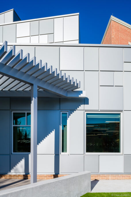 Exterior metal panel facade with pergola canopy detail on Houston private school new addition, bright blue sky backdrop