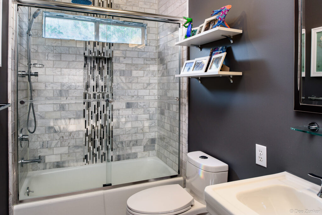 Modern Houston bathroom with marble subway tile shower mosaic accent glass doors floating shelves and dark accent wall