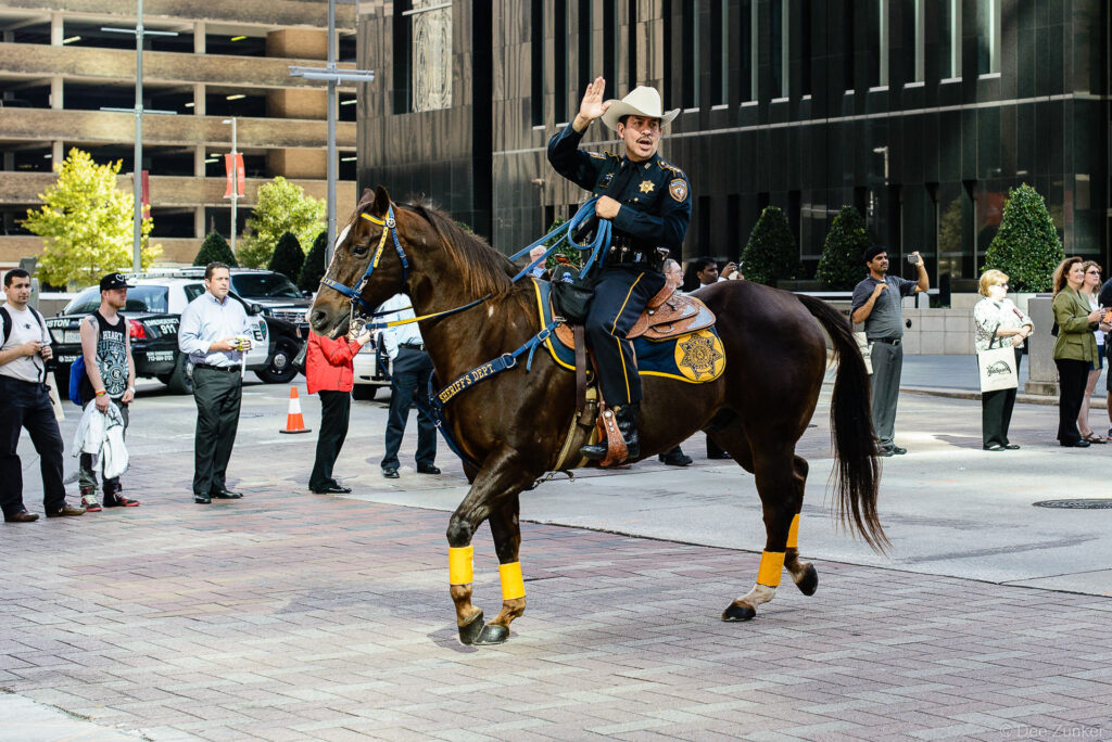 Houston Sheriff's Department mounted patrol officer on horseback waves to crowd during corporate event in downtown Houston.