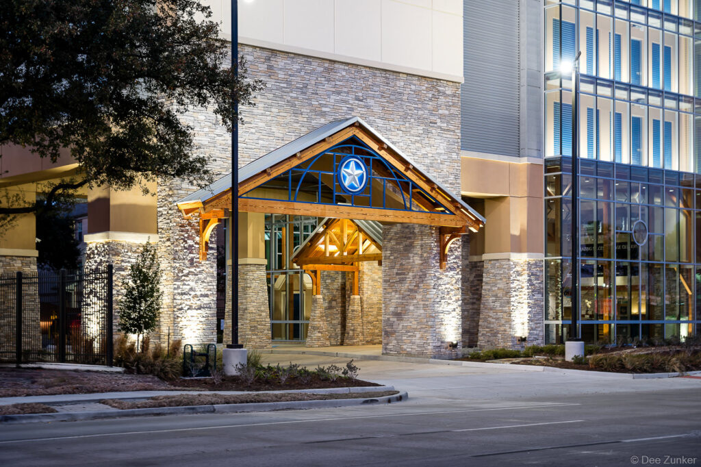 Illuminated stone and timber entrance canopy with lone star emblem at a Houston storage facility near Greenway Plaza, photographed at dusk