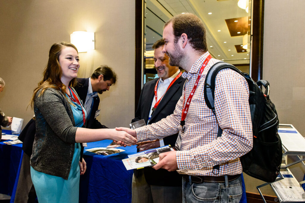 Attendees shake hands and exchange materials at the Houston IT Symposium a corporate event captured by Houston event photographer.