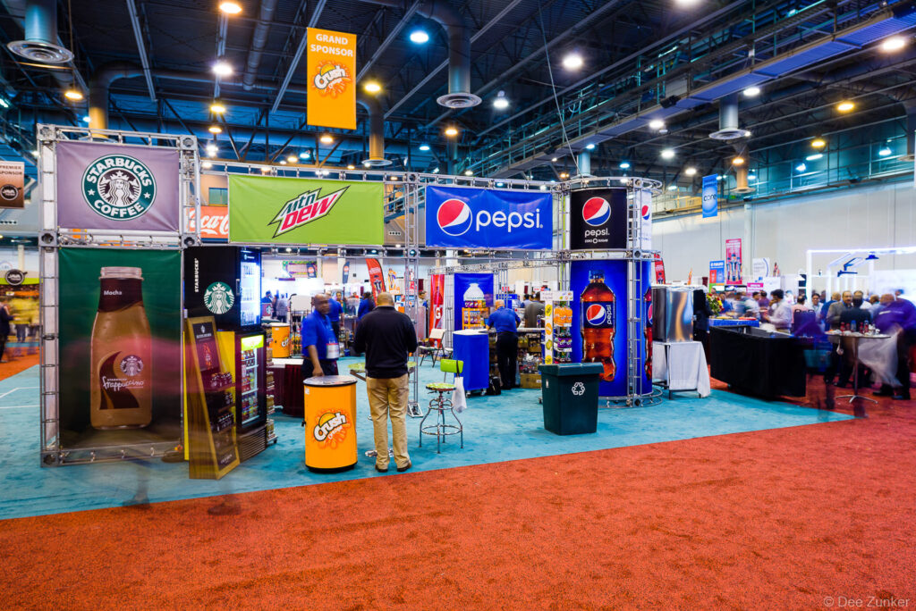 Beverage brand trade show exhibit booths with colorful signage on the convention floor at a Houston GHRA industry event.