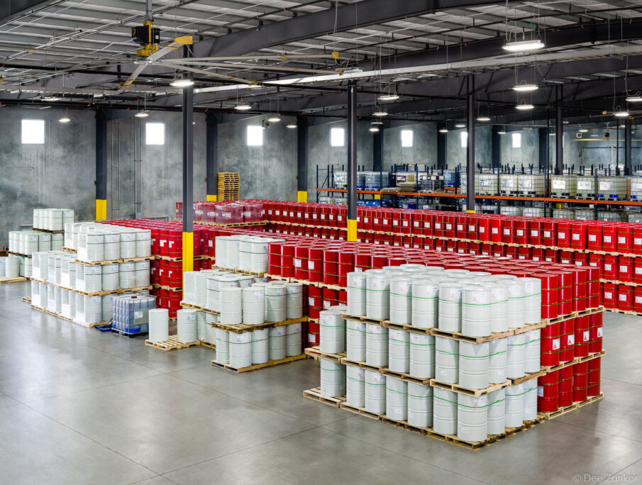 Large industrial warehouse interior with rows of stacked red and white drums on pallets, Houston commercial photography