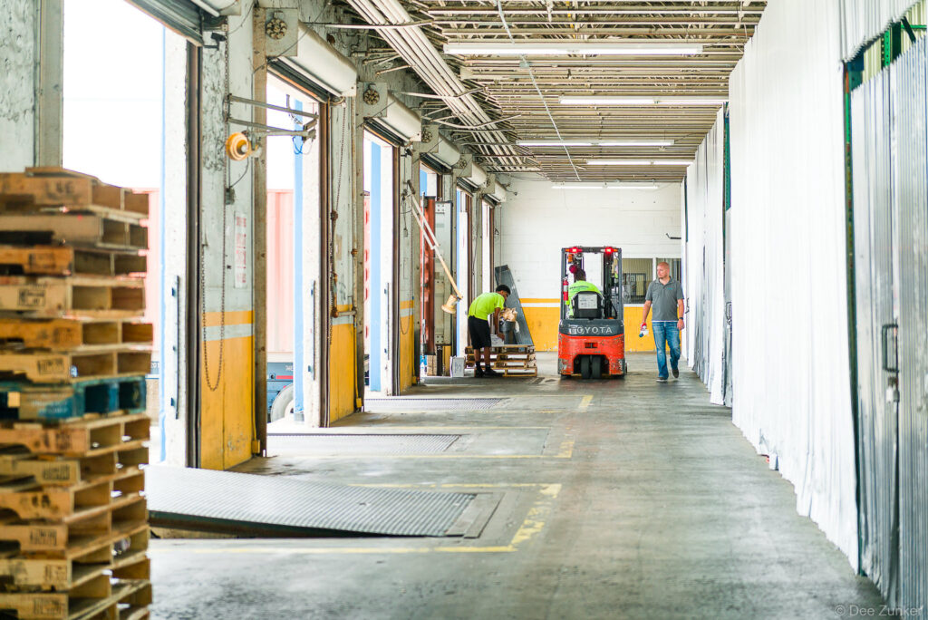 Workers and a Toyota forklift operate along a loading dock corridor inside a Houston industrial warehouse facility.