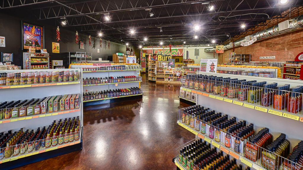 Interior of a specialty hot sauce retail shop in Bellaire TX featuring shelves packed with colorful bottles and sauces