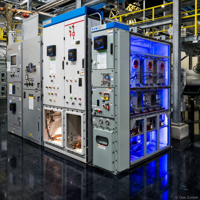 Illuminated low-voltage switchgear lineup with blue LED lighting and open control panels inside a Houston industrial facility.