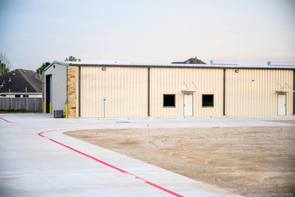Exterior view of a metal panel industrial warehouse building with stone accents and concrete apron on FM 529, Houston TX.