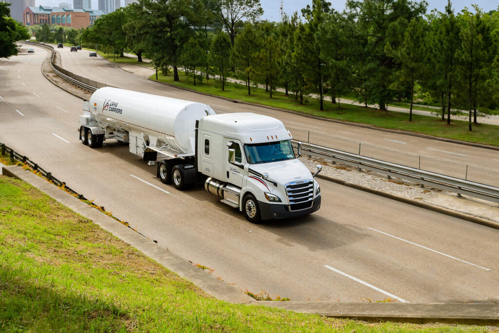 White semi-truck hauling a cryogenic liquid gas tanker trailer on a Houston highway, photographed for industrial transportation portfolio.