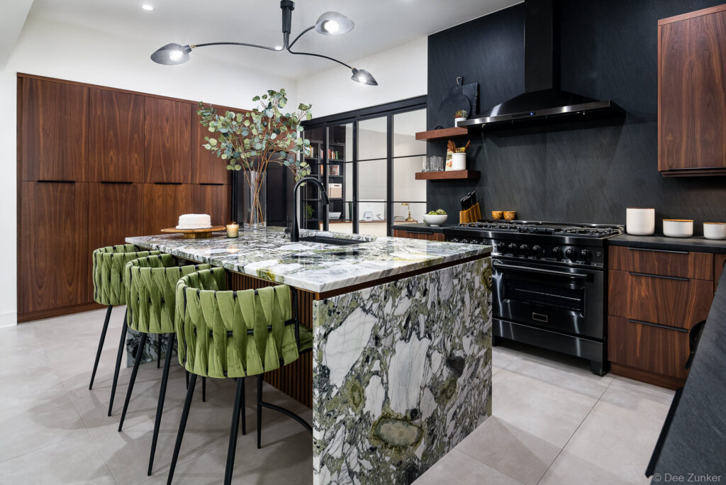Upscale Houston kitchen with green marble island, velvet bar stools, walnut cabinetry, and black range in a luxury interior design project.
