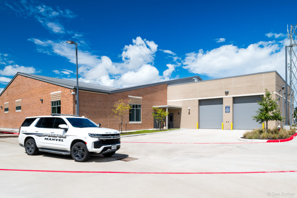 Exterior view of a new Manvel Texas police station featuring brick and stone facade with patrol SUV parked in foreground