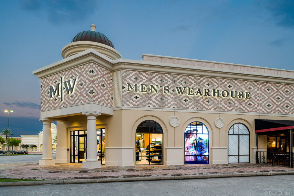 Exterior twilight view of a concept menswear retail store in Shenandoah TX featuring ornate facade and illuminated arched windows