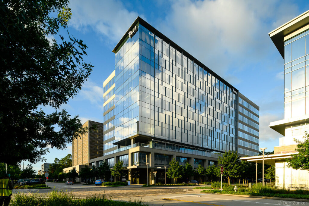 Modern glass office tower exterior photographed at golden hour in The Woodlands TX showcasing curtain wall facade and landscaped streetscape