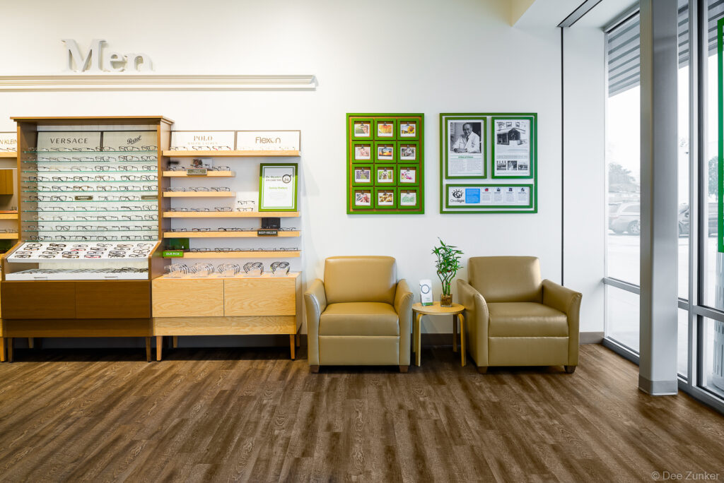 Pearle Vision optical store interior showing men's eyeglass display frames, waiting area with tan armchairs, and branded wall art in Houston.