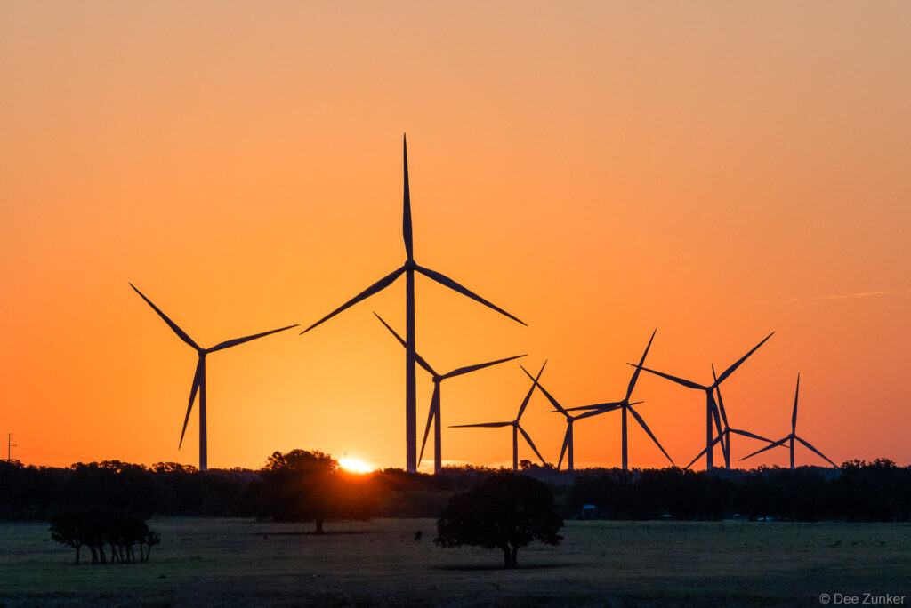 Wind turbines silhouetted against a vivid orange sunrise at Rattlesnake Wind Farm in central Texas renewable energy landscape
