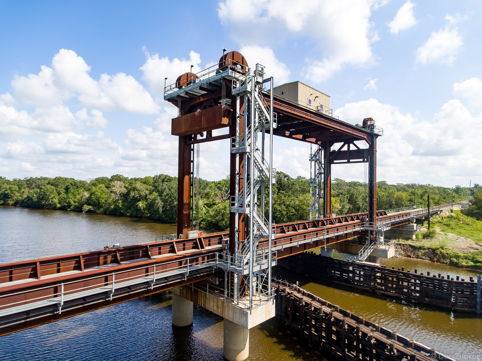 Aerial view of San Bernard River vertical lift railroad bridge, rust-patinated steel tower with machinery, Houston Texas region.