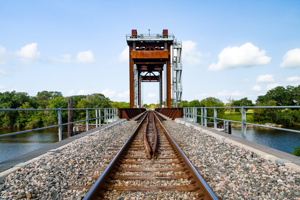 Aerial view along railroad tracks crossing the San Bernard River on a vertical lift bridge in Texas, shot for infrastructure portfolio.