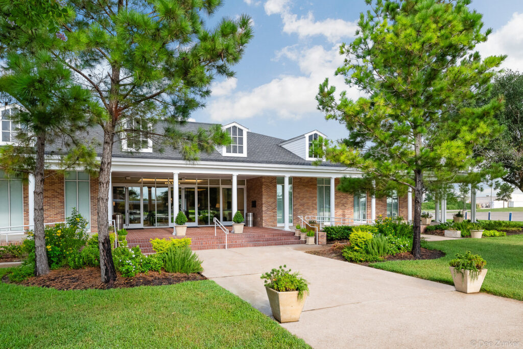 Brick exterior entrance of a church facility in Katy TX featuring a covered portico pine trees and manicured landscaping