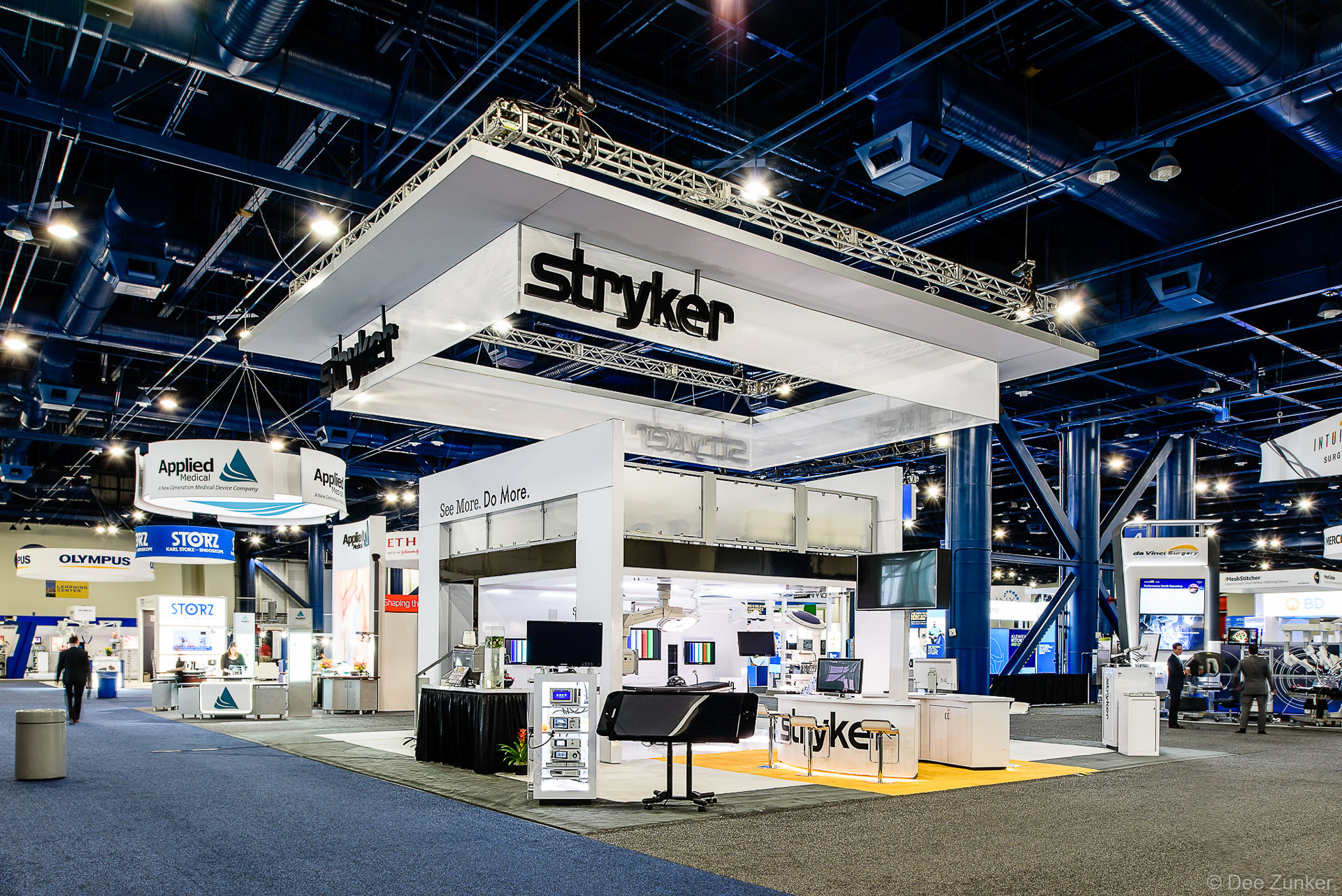 Large two-story Stryker medical equipment exhibit booth with overhead signage at a Houston convention center trade show, photographed by Dee Zunker Photography.