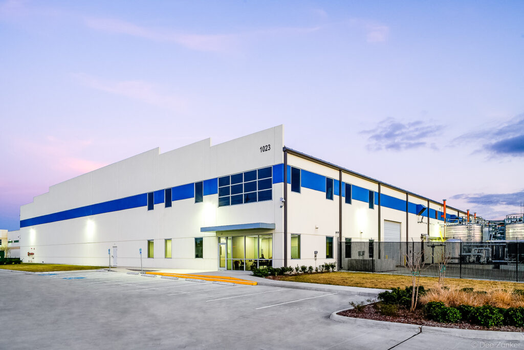Twilight exterior of NCFI SeaChange commercial warehouse, white and blue facade with parking lot, Houston TX.